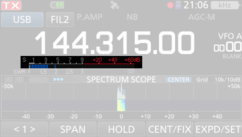 1) Kurzbeschreibung: Display eines Funkgerätes mit Frequenzanzeige „144.315.00“, darunter eine hervorgehobene SWR-Anzeige; Spektrums- und Wasserfalldarstellung eines starken Signals in der Mitte.
2) Ausführliche Beschreibung: Die Abbildung zeigt das Display eines Funkgerätes auf schwarzem Untergrund. Neben weiteren Beschriftungen steht in der Mitte in großen, weißen Ziffern die Frequenz „144.315.00“. Darunter befindet sich eine SWR-Anzeige. Unter der SWR-Anzeige ist in blauer Farbe die Anzeige des Spektrums um die eingestellte Frequenz zu sehen, die von den Angaben „–50k“ (links) und „+50k“ (rechts) begrenzt wird. In der Mitte gibt es einen schmalen, hohen Peak mit kleineren Flanken. Darunter befindet sich ein Wasserfalldiagramm auf dunkelblauem Hintergrund mit einer hellblau-weißen vertikalen Spur unterhalb des Peaks. Die SWR-Anzeige ist hervorgehoben, der Rest der Abbildung ist abgeblendet.